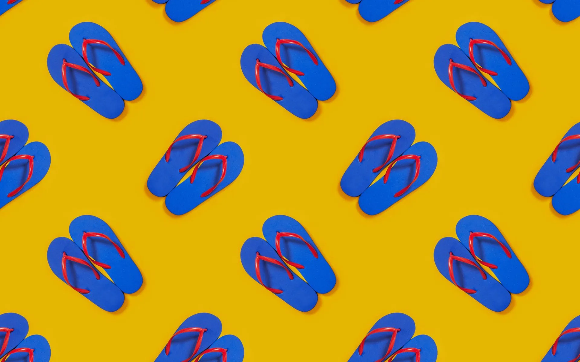 Pattern of blue flip flops with red straps on a yellow background