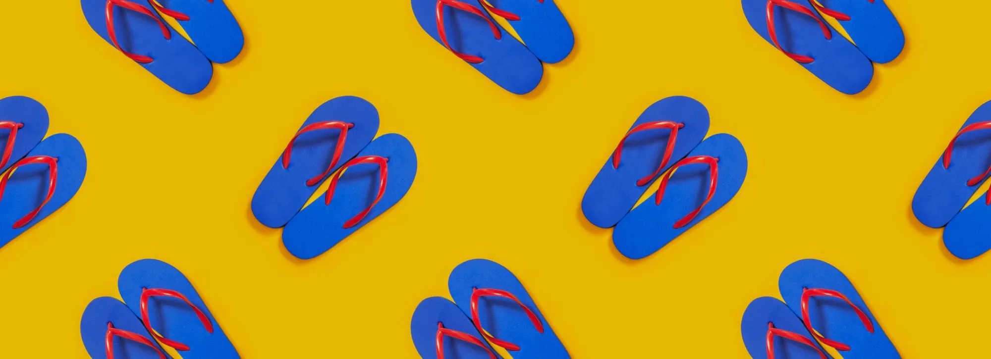 Pattern of blue flip flops with red straps on a yellow background